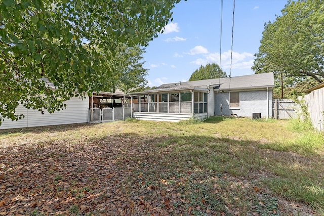 rear view of property with a sunroom, a carport, and a lawn