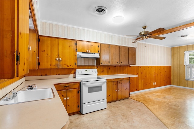 kitchen with a textured ceiling, sink, wood walls, white electric range oven, and ceiling fan