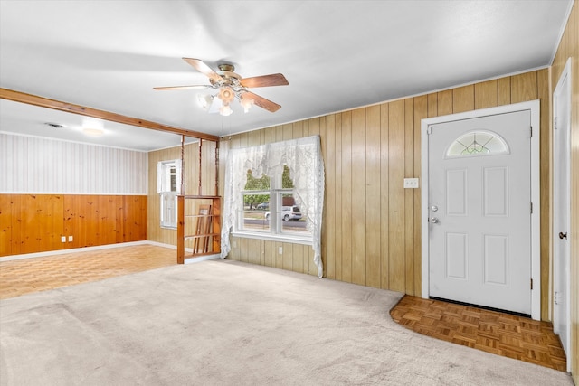 foyer entrance with ceiling fan, parquet flooring, and wood walls