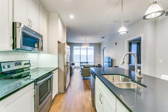 kitchen featuring stainless steel appliances, white cabinets, hanging light fixtures, and dark hardwood / wood-style flooring