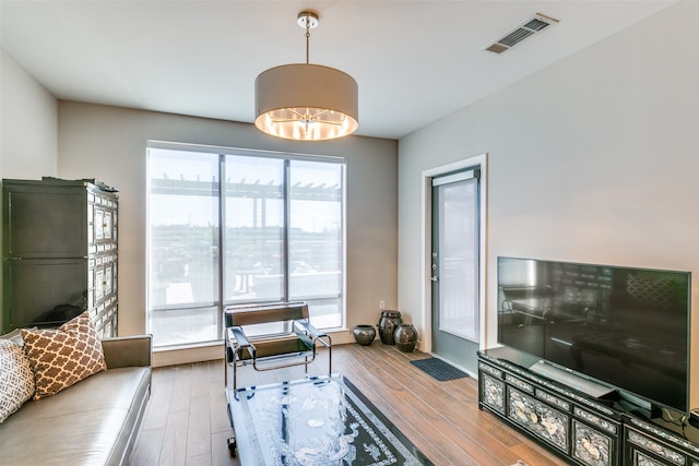 living room featuring wood-type flooring, a notable chandelier, and plenty of natural light