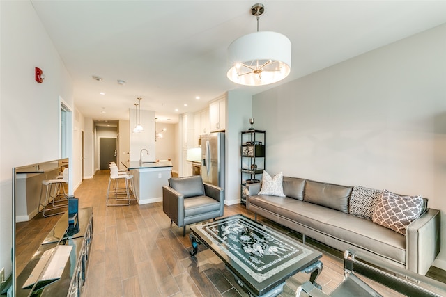 living room featuring a notable chandelier, hardwood / wood-style flooring, and sink