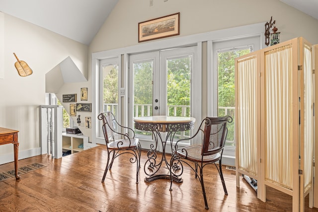 dining space with high vaulted ceiling, a wealth of natural light, and hardwood / wood-style floors