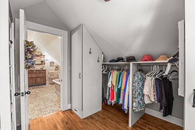 walk in closet featuring hardwood / wood-style flooring and vaulted ceiling