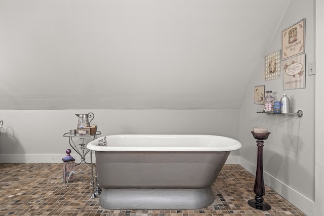 bathroom featuring a tub to relax in and vaulted ceiling