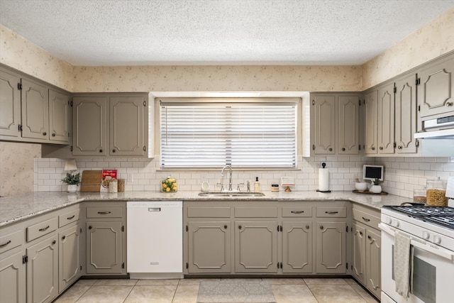 kitchen with light tile patterned flooring, tasteful backsplash, white appliances, a textured ceiling, and sink