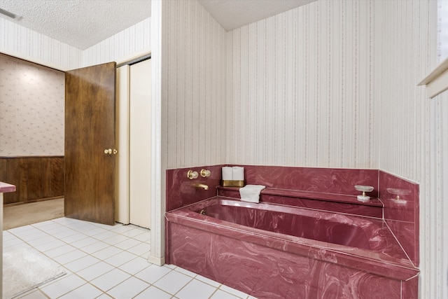 bathroom with tile patterned floors, a textured ceiling, and a bathtub