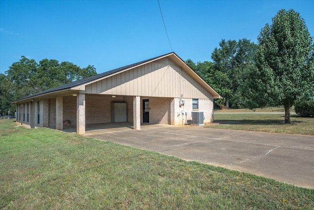 garage featuring a carport, central air condition unit, and a yard