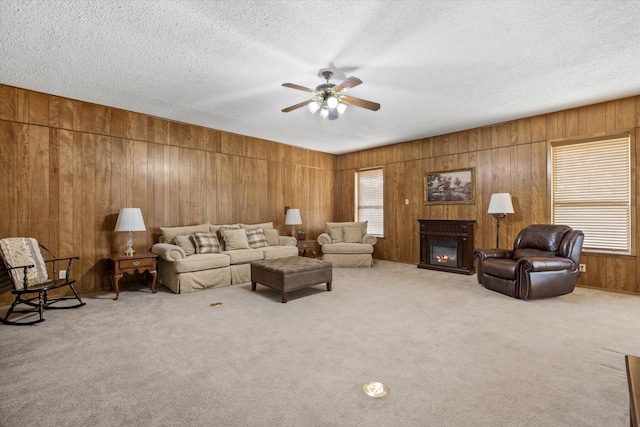 carpeted living room featuring a textured ceiling, wood walls, and ceiling fan