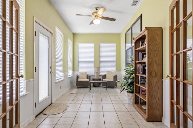 living area featuring ceiling fan, a textured ceiling, french doors, and light tile patterned flooring