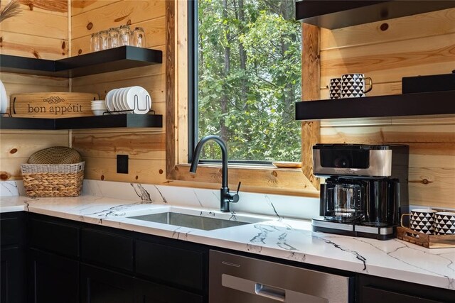 kitchen featuring wooden walls, open shelves, a sink, dishwasher, and dark cabinets