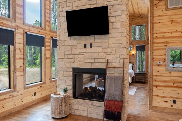 living area with visible vents, wooden walls, wood finished floors, and a fireplace