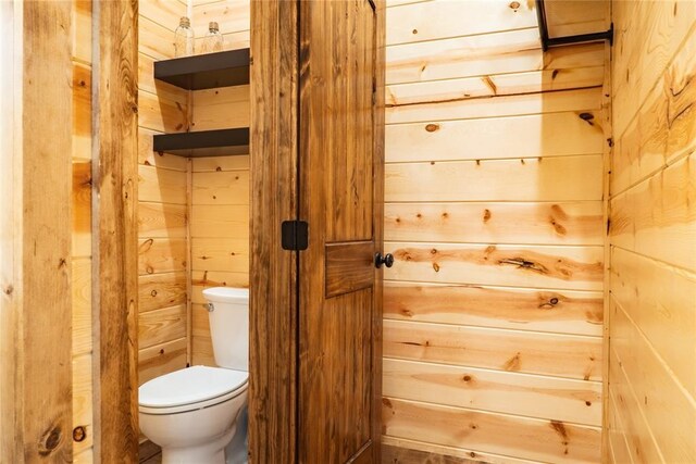 half bath with toilet and wood walls