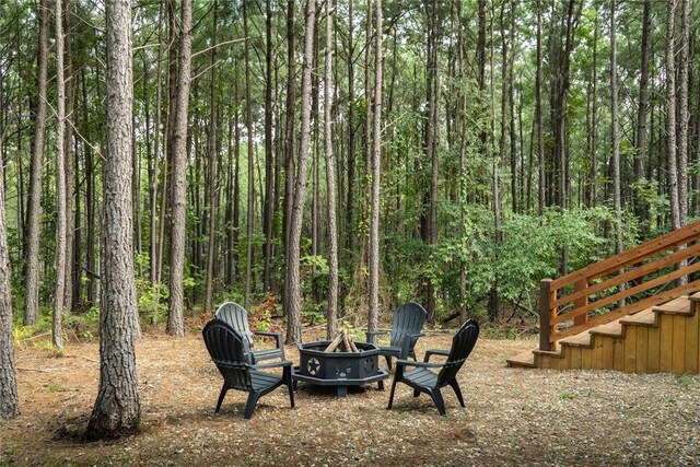 view of yard featuring a view of trees and an outdoor fire pit