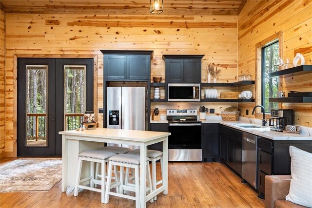 kitchen featuring a sink, light countertops, light wood-style flooring, appliances with stainless steel finishes, and open shelves