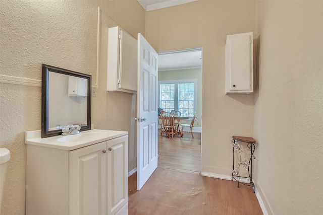 corridor with ornamental molding, hardwood / wood-style floors, and sink