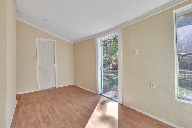 spare room with light wood-type flooring, ornamental molding, and vaulted ceiling