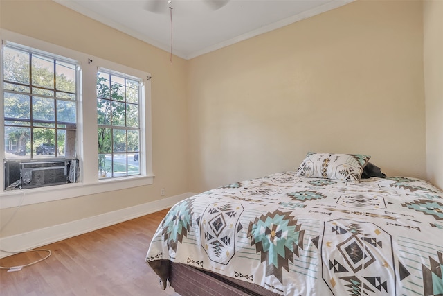 bedroom featuring cooling unit, ornamental molding, hardwood / wood-style floors, and ceiling fan