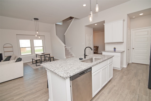 kitchen featuring pendant lighting, a center island with sink, sink, and stainless steel dishwasher