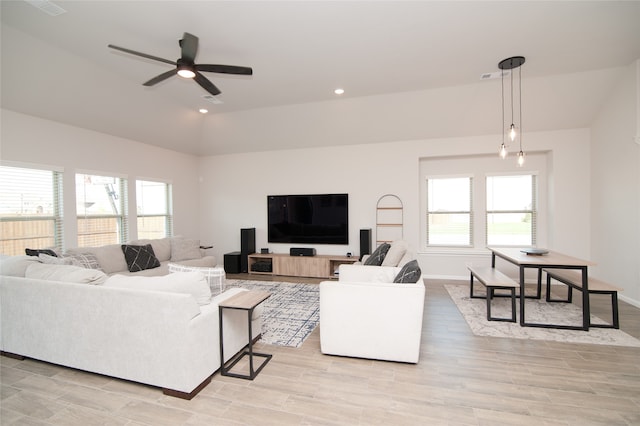 living room with a healthy amount of sunlight, vaulted ceiling, ceiling fan, and light hardwood / wood-style flooring