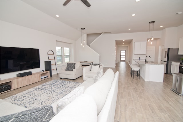 living room featuring ceiling fan, light hardwood / wood-style flooring, sink, and lofted ceiling