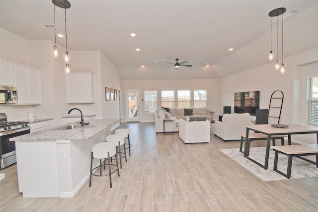 kitchen featuring appliances with stainless steel finishes, white cabinetry, ceiling fan, decorative light fixtures, and sink