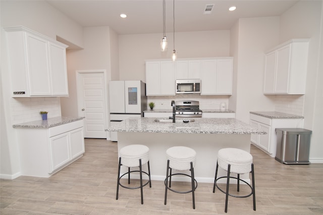 kitchen with light stone countertops, stainless steel appliances, and white cabinets