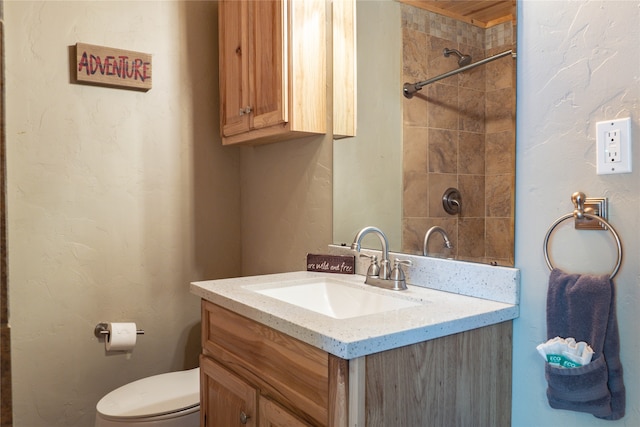 bathroom with vanity, toilet, and tiled shower