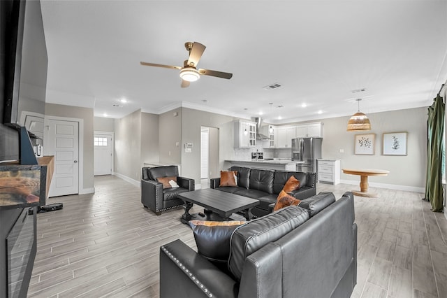 living room with light wood-type flooring, ceiling fan, and crown molding