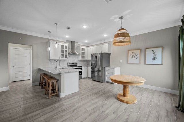 kitchen with wall chimney exhaust hood, kitchen peninsula, pendant lighting, white cabinets, and appliances with stainless steel finishes