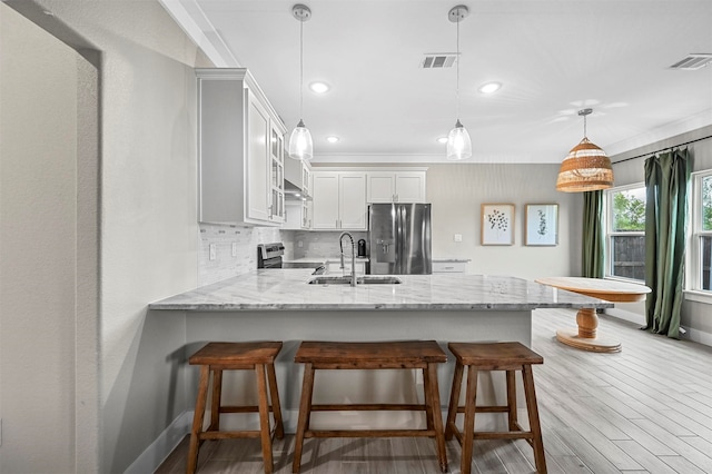 kitchen featuring white cabinetry, sink, stainless steel appliances, backsplash, and decorative light fixtures