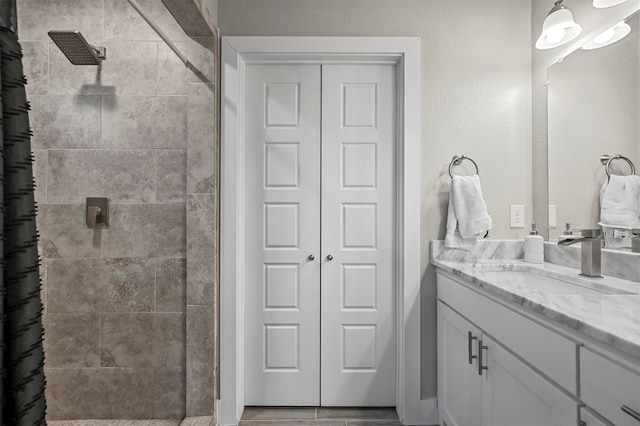 bathroom with a tile shower and vanity