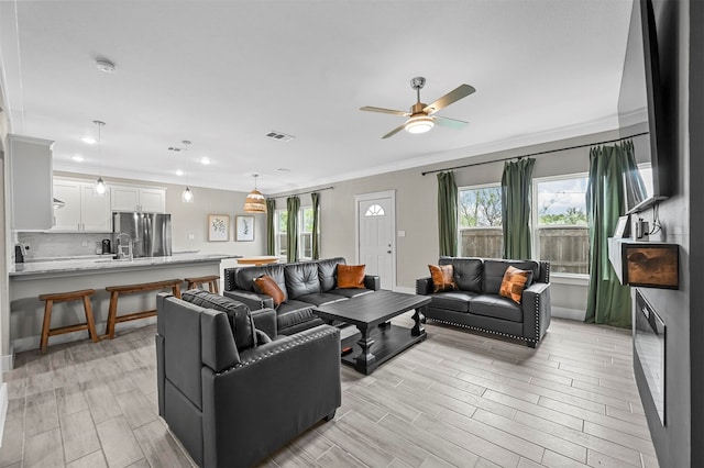 living room featuring a wealth of natural light, ceiling fan, and ornamental molding