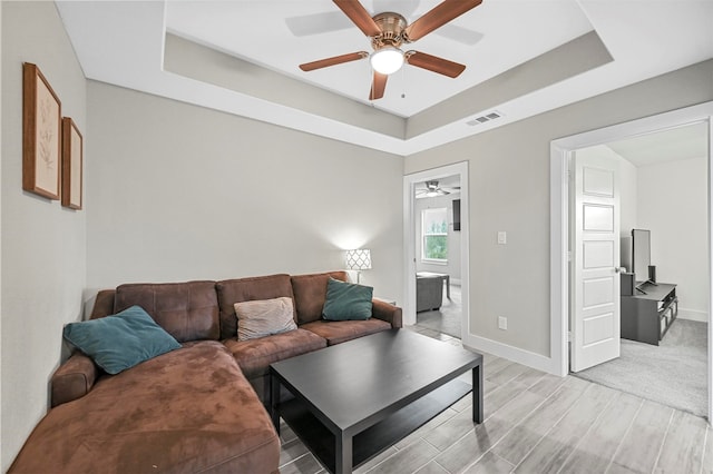 living room featuring ceiling fan and a tray ceiling