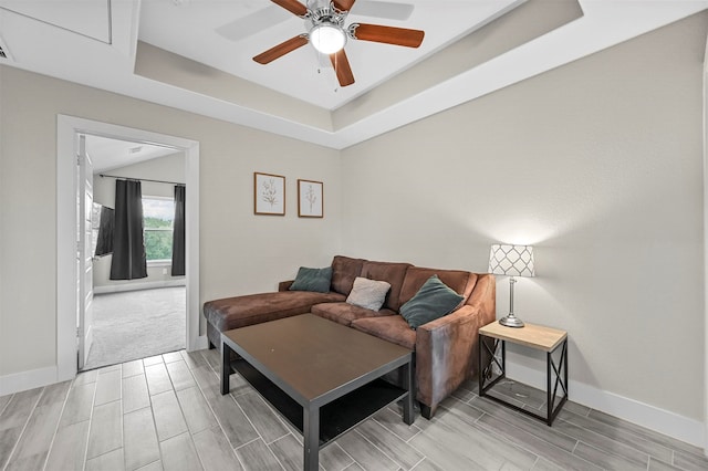 living room featuring a tray ceiling and ceiling fan