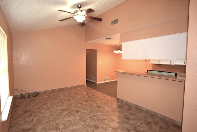 interior space featuring ceiling fan with notable chandelier, a textured ceiling, high vaulted ceiling, and tile patterned flooring