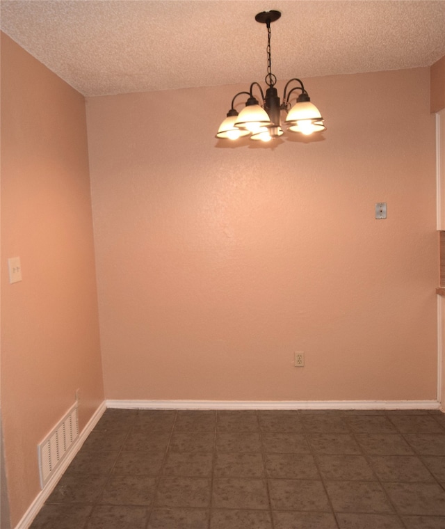 unfurnished room with a textured ceiling and a notable chandelier