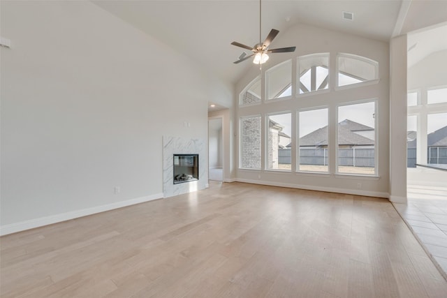 unfurnished living room with light wood-style floors, a fireplace, a ceiling fan, and a wealth of natural light