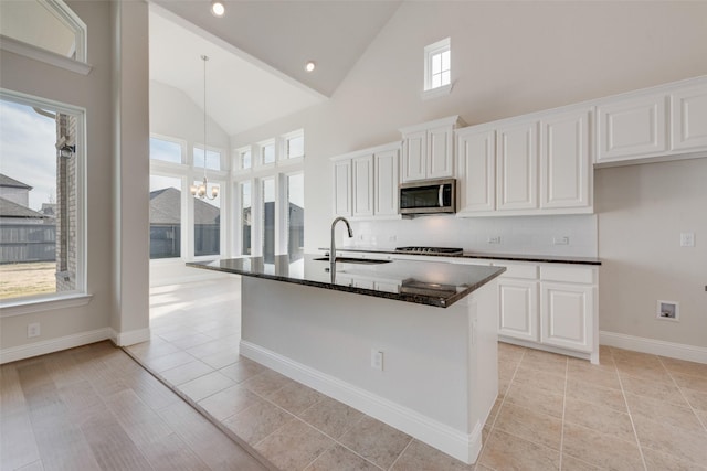 kitchen featuring white cabinetry, light tile patterned flooring, a kitchen island with sink, and sink