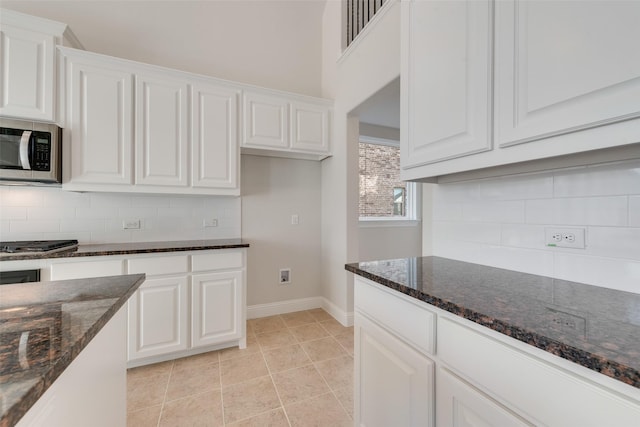 kitchen with dark stone countertops, stainless steel appliances, and white cabinets