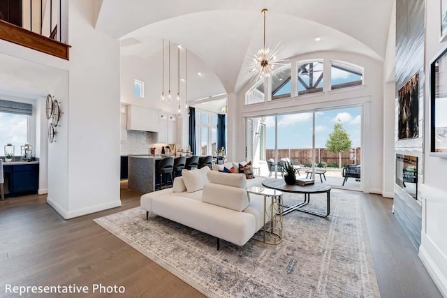 living room with high vaulted ceiling, wood-type flooring, and a notable chandelier