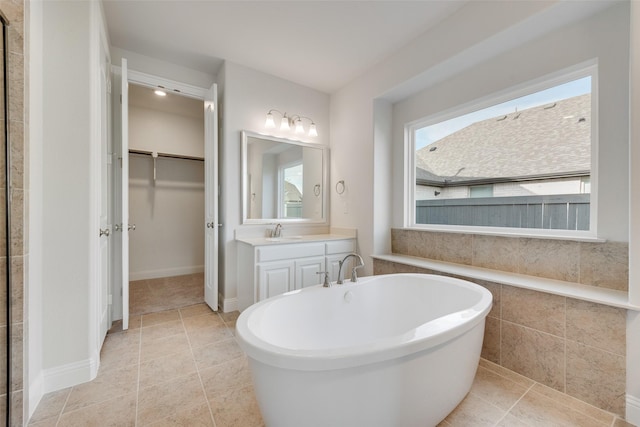 bathroom with a tub to relax in, tile patterned flooring, and vanity