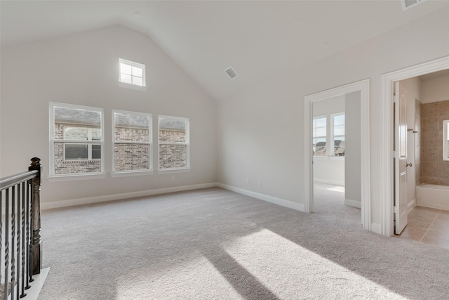 additional living space with a wealth of natural light, vaulted ceiling, and light carpet