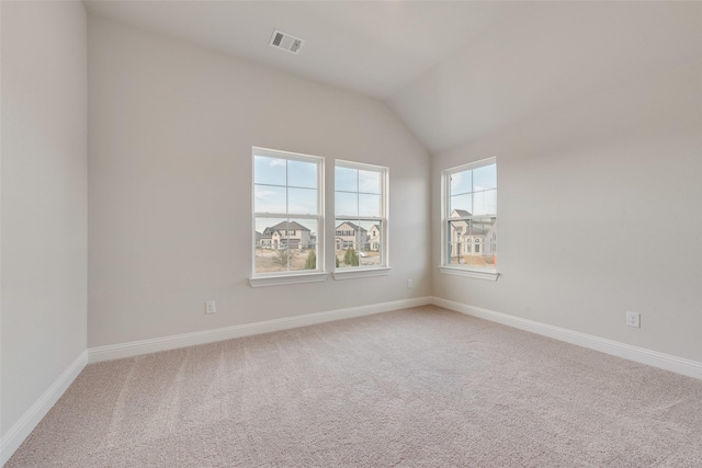 carpeted spare room featuring vaulted ceiling