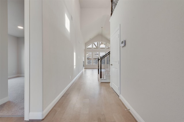 hall with a towering ceiling and light hardwood / wood-style floors