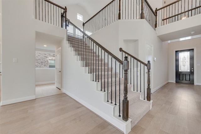 foyer entrance featuring light wood-type flooring, plenty of natural light, and a high ceiling