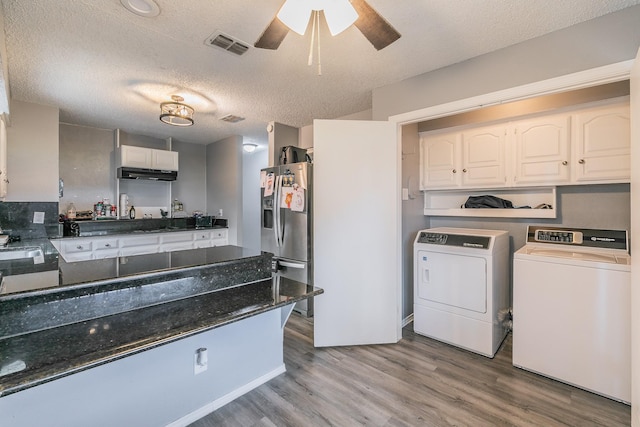 205 Benwynd Dr, Mesquite, TX 75149 - kitchen with stainless steel refrigerator with ice dispenser, washing machine and clothes dryer, under cabinet range hood, wood finished floors, and white cabinetry