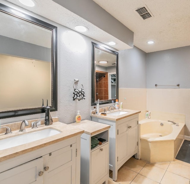 bathroom featuring vanity, a tub, tile patterned floors, and a textured ceiling