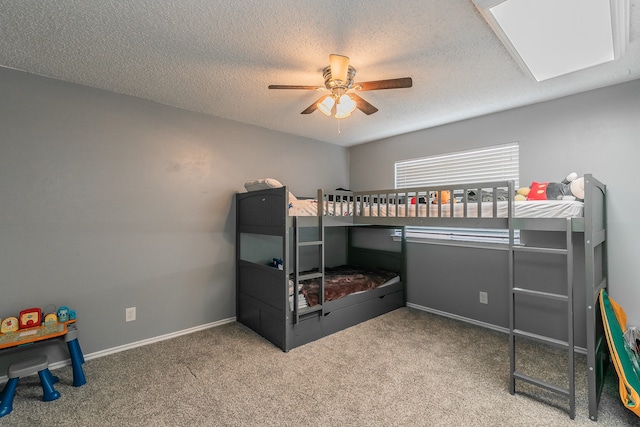 bedroom with ceiling fan, a textured ceiling, a skylight, and carpet