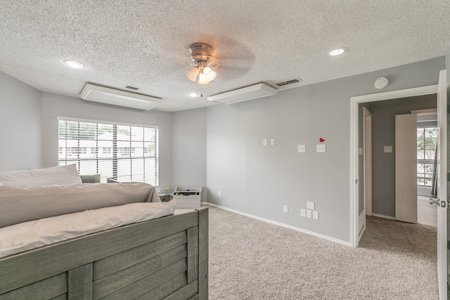 bedroom featuring multiple windows, a textured ceiling, light colored carpet, and ceiling fan